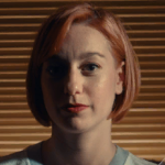 ellis, a woman with short straight red hair and red lipstick